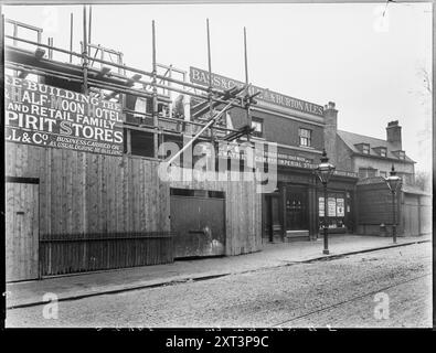 French Horn and Half Moon Hotel, East Hill, Wandsworth, Wandsworth, Greater London Authority, c1900. Der Wiederaufbau des French Horn and Half Moon Hotels auf East Hill. Dieses Foto zeigt das neue Horn und den Halbmond, das sich im Bau befindet, in kurzer Entfernung östlich des bestehenden Wirtshauses (in der Mitte dieser Ansicht gesehen). Das ursprüngliche Gebäude wurde kurz darauf abgerissen, um den Bau der Woodwell Street zu ermöglichen. Das neue French Horn and Half Moon wurde später abgerissen, um Platz für die A214 Trinity Road zu schaffen. Auf dem Gerüst des neuen Gebäudes steht: "BUSINESS Stockfoto