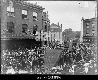 Wandsworth High Street, Wandsworth, Wandsworth, Greater London Authority, 1890-1910. Menschenmassen versammelten sich, um eine Prozession der Sunday School auf der Wandsworth High Street zu beobachten, in der Nähe der Kreuzungen RAM Street, Garratt Lane und Buckhold Road. In dieser Szene blickt der Fotograf von der Wandsworth High Street nach Südwesten, und das Spread Eagle Hotel befindet sich auf der linken Seite. Das geschwungene Gebäude in der Mitte des Shot ist 75 Wandsworth High Street, an der Ecke Garratt Lane. Geradeaus verläuft die ehemalige Buckhold Road, die dann umgeleitet wurde, um Platz für das Southside Shopping Center zu schaffen Stockfoto