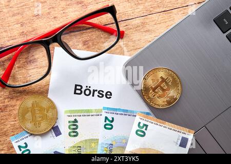 13. August 2024: Symbolisches Bild des Börsenhandels. Euro-Scheine, Bitcoin-Münzen und eine Brille, die neben einem Laptop liegt *** Symbolbild Händel an der Börse. Euroscheine, Bitcoin-Münzen, eine Brille liegt neben einem Laptop Computer Stockfoto