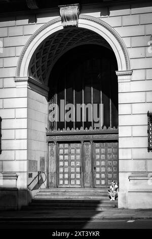 Eine junge tätowierte Frau sitzt auf den Stufen des alten Martins Bank-Gebäudes in Liverpool und liest ihr Handy Stockfoto