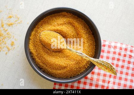 Nahaufnahme von braunem Zucker auf goldenem Löffel über weißem Hintergrund, Draufsicht Stockfoto