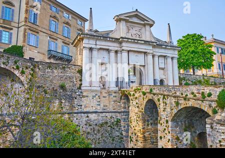 Das mittelalterliche, skulpturierte Tor Porta San Giacomo und die Bogenbrücke (Viadukt) verbinden es mit der Unterstadt und erstrecken sich über den grünen Park Bergam Stockfoto