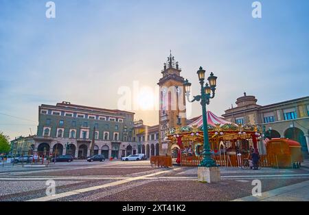 Der trübe Sonnenuntergang über der Piazza Vittorio Veneto mit Vintage-Straßenlaterne, Karussell und Gedenkturm im Hintergrund, Bergamo, Italien Stockfoto