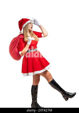 Junge blonde Frau santa claus, die die Straße mit einer Tüte Geschenke an weihnachten auf weißem Hintergrund sieht Stockfoto