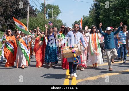 Unter der Leitung eines Schlagzeugers feiert eine fröhliche Gruppe von Märschen den Jahrestag der Unabhängigkeit Indiens bei der New City India Day Parade. Stockfoto