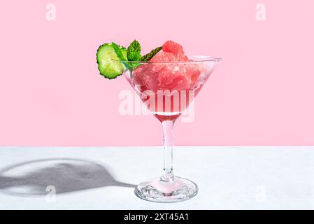 Wassermelonen-Slushie oder Granita-Cocktail mit Minze- und Gurkenscheibe im Glas auf rosa Hintergrund. Erfrischende kalte Beeren Sommer rasiertes Eisgetränk, Trend Stockfoto