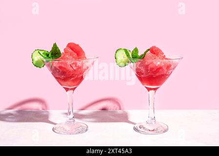 Wassermelonen-Slushie- oder Granita-Cocktail-Drink mit Minze in zwei Gläsern auf rosa Pastellhintergrund, Vorderansicht, Kopierraum. Erfrischende kalte Sommerrasur Stockfoto