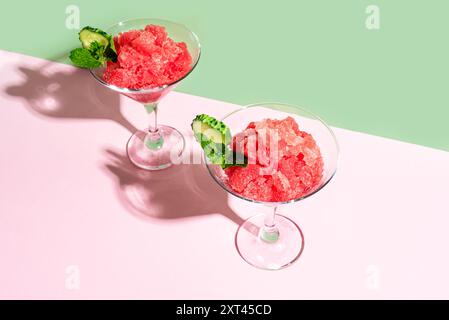 Wassermelonen-Slushie oder Erdbeer-Granita-Cocktail mit Minze in Gläsern auf rosafarbenem und grünem kreativem Hintergrund. Erfrischendes kaltes, im Sommer rasiertes Eissorbe Stockfoto