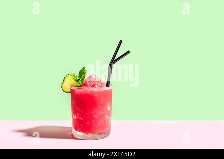 Wassermelonen-Slushie oder Erdbeer-Granita-Cocktail mit Minze in Gläsern auf rosafarbenem und grünem kreativem Hintergrund. Erfrischendes kaltes, im Sommer rasiertes Eissorbe Stockfoto