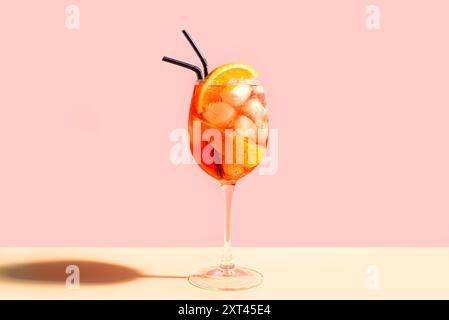 Aperol Spritz Cocktail im Glas mit orangefarbenen Scheiben auf rosa pfirsichfarbenem Hintergrund, minimaler trendiger Schuss. Alkohol Aperol Spritz Aperetivo. Stockfoto