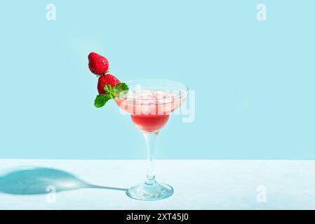 Erdbeermartini oder Daiquiri Cocktail im Glas mit Minze und frischen Erdbeeren auf blauem Pastellhintergrund, Kopierraum. Trendiges Konzept von Cocktail PA Stockfoto
