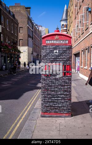 Eine versiegelte und unbrauchbare rote Telefonbox in Soho mit Klebeband und Fotoaufkleber. Stockfoto