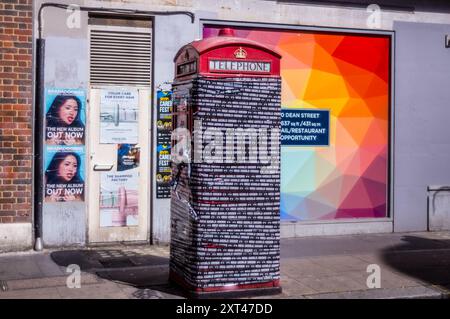 Eine versiegelte und unbrauchbare rote Telefonbox in Soho mit Klebeband und Fotoaufkleber. Stockfoto