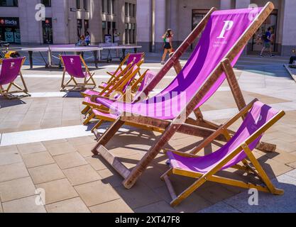 Riesige und kleine pinkfarbene Liegestühle in der Sommersonne auf dem kleinen Platz des Paternoster Square neben der Saint-Paul's Cathedral in London. Stockfoto