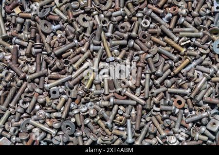 Nahaufnahme eines chaotischen Sortiments verschiedener Metallscheiben, Schrauben, Muttern und Bolzen, die auf einer Oberfläche verstreut sind und unterschiedliche Größen und Texturen zeigen. Stockfoto