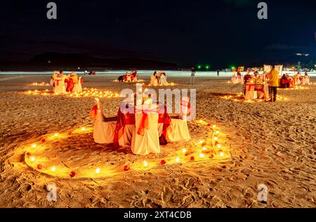 Langkawi Island, Malaysia-Mai 05 2023: Abends nach Sonnenuntergang werden am Sandstrand Tische und Stühle des Restaurants in glitzerndem Glanz angeordnet Stockfoto