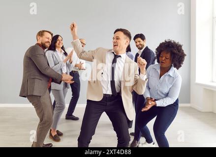 Glückliche Kollegen im Büro haben Spaß, verschiedene gemischte Freunde tanzen zusammen und feiern Stockfoto