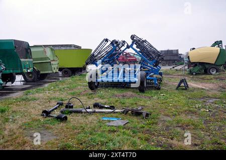 Eine Deponie von Landmaschinen, Komponenten und Baugruppen im Hinterhof einer landwirtschaftlichen Organisation. Stockfoto