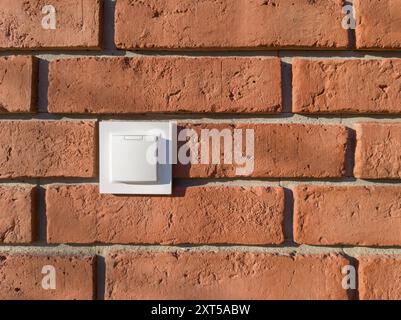 Weiße Steckdose an der roten Ziegelwand Stockfoto