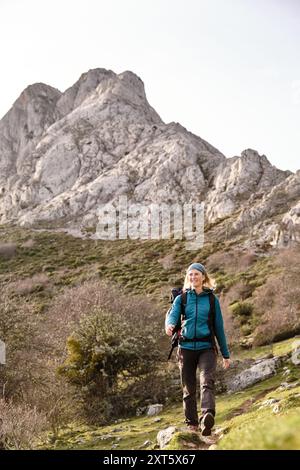 Lächelnder Wanderer, der mit einem Berg im Hintergrund spaziert Stockfoto