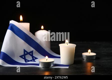 Brennende Kerzen und Flagge Israels auf dunklem Hintergrund. Holocaust-Gedenktag Stockfoto