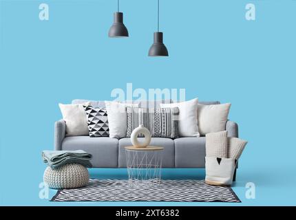 Komfortables graues Sofa mit Kissen und Lampen auf blauem Hintergrund Stockfoto