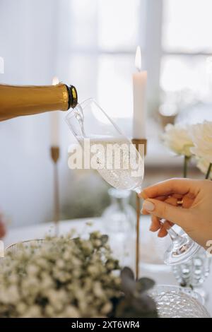 Kellnerin gießt Champagner aus der Flasche in ein Glas im Restaurant. Feierliche Veranstaltung Stockfoto