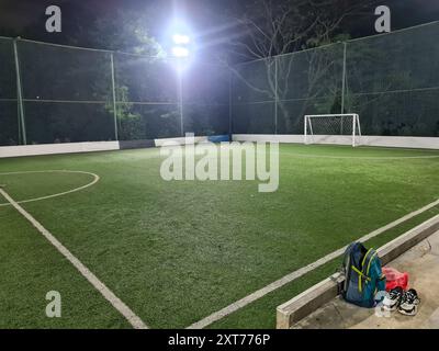 Sportschuh und -Tasche auf leerem Futsal- oder Mini-Fußballfeld mit Tor und hohem Netz. Stockfoto