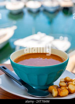 Hausgemachte leckere Fisch- oder Bisquesuppe mit Croutons im Freien und Blick auf Yachtboote und Häuser von Port Grimaud, französische Riviera. Lebensmittel von PR Stockfoto