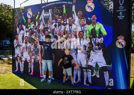 Die Fans von Real Madrid posieren für ein Foto vor dem Siegerteam der Champions League 2024. Die Fans der spanischen Champions-League-Gewinner Real Madrid und der italienischen UEFA-Cup-Gewinner Atalanta trafen sich auf dem Kahla-Platz in Warschau neben der Weichsel zum UEFA-Super-Cup-Fanfestival. Im Vorgriff auf das Spiel am folgenden Tag stehen die Besucher an, um Fotos mit der Trophäe zu machen und an einer Reihe von Fußballspielen und -Aktivitäten teilzunehmen. Der UEFA-Supercup findet am 14. August 2024 im PGE Narodowy in Warschau statt und wird von den Gewinnern der Champions League und des UEFA Cup wi bestritten Stockfoto