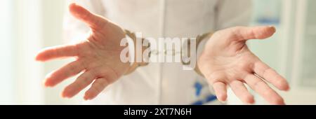 Arzt mit Stethoskop in Handschellen. Krankenschwester mit Metallhandschellen an den Händen Stockfoto