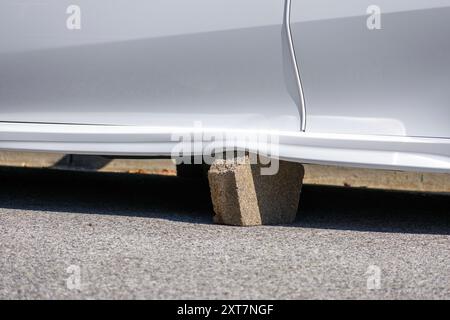Ein weißer Fahrzeugrahmen, der durch einen Betonblock gestützt und beschädigt wurde, nachdem Räder gestohlen wurden. Nahaufnahme Stockfoto