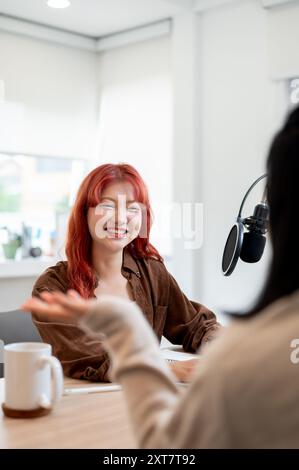 Eine selbstbewusste und freundliche asiatische Podcasterin macht ein Gespräch, während sie einen Gast in ihrem Studio interviewt und einen Podcast mit einem Special aufnimmt Stockfoto