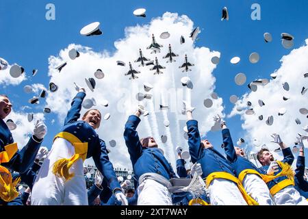 Die Absolventen der U.S. Air Force Academy der Klasse 2024 werfen ihre Hüte in den Himmel, während die U.S. Air Force Thunderbirds im Falcon Stadium in Color über ihnen brüllen Stockfoto