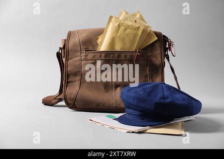 Braune Brieftasche, Briefumschläge, Zeitungen und Hut auf grauem Hintergrund Stockfoto