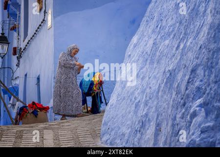 Chefchaouen, marokkanische Frau mit einem wunderschönen traditionellen Lächeln, während sie nach einem Verkauf Geld zählt. Straßenszene in der blauen Stadt Medi Stockfoto