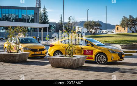 Straßenszene mit geparkten Taxis am Tirana International Airport in Albanien. Taxis stehen auf einer Straße und warten auf Touristen, die am Flughafen ankommen. Stockfoto