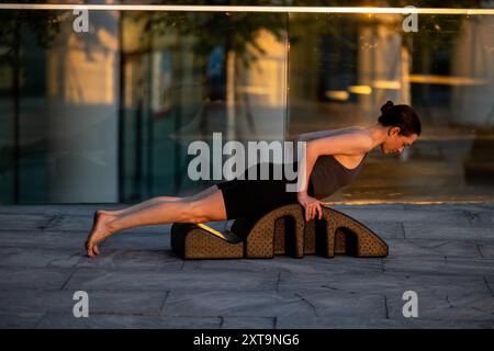 Fitte Frau, die draußen Pilates auf Bogenfass macht Stockfoto