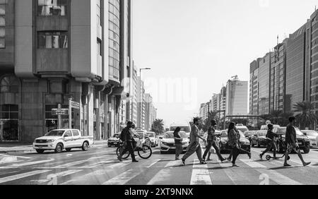 Menschen gehen auf Zebras durch Straßen Abu Dhabi VAE während der Hauptverkehrszeit im städtischen Geschäftsviertel. Leute, die die Straße überqueren. Geschäftige Stadtstraße Stockfoto