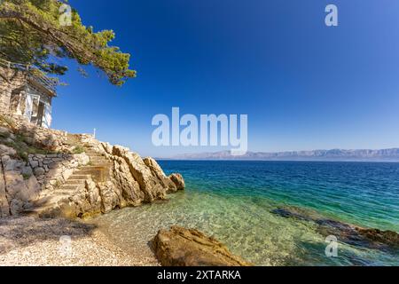 Steiler Abstieg die Treppe hinunter zu einem felsigen Strand, Adriaküste in Kroatien, Sicherheitsgeländer aus dickem Angelseil Stockfoto