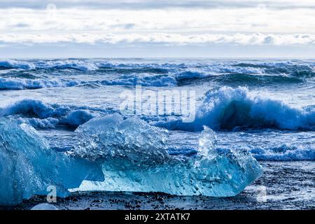 Das Meer ist blau und die Wellen stürzen gegen Eisblöcke. Das Wasser ist kalt und das Eis schwimmt darüber Stockfoto