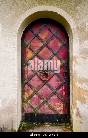 Alte verrostete Metalltür mit einem Türklopfer. Antiker Eingang mit Rundbogen. Stockfoto