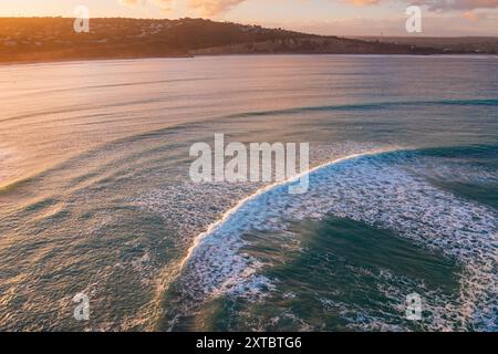 Aus der Vogelperspektive von Wellen, die in der Abenddämmerung sanft in eine Küstenbucht in der Nähe von Point Roadknight an der Great Ocean Road in Victoria, Australien, Rollen. Stockfoto