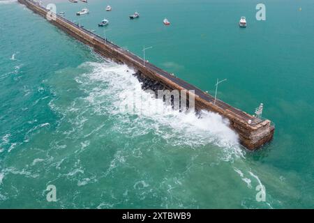 Aus der Vogelperspektive einer großen Welle, die bei Warrnambool an der Great Ocean Road in Victoria, Australien, auf eine Küstenmole stürzt. Stockfoto