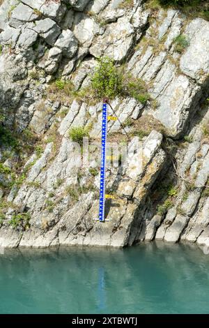 Wasserstandsmessung auf felsigem Gelände neben einem ruhigen Fluss Stockfoto