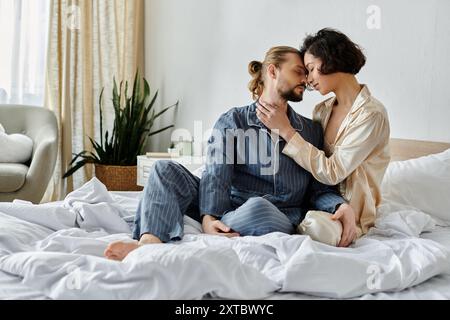 Ein liebevolles Paar im Pyjama kuschelt sich an ein weißes Bett. Stockfoto