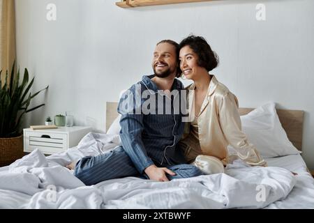 Ein liebevolles Paar im Pyjama sitzt auf dem Bett, kuschelt und entspannt. Stockfoto