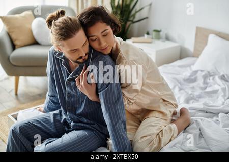 Ein liebevolles Paar im Pyjama kuschelt sich an ein Bett. Stockfoto
