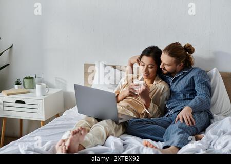 Ein paar entspannte Gäste im Bett mit Kaffee und im Internet surfen. Stockfoto