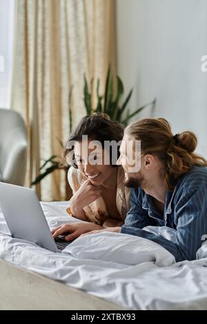 Ein liebevolles Paar verbringt Zeit zu Hause, entspannt im Bett und surft auf einem Laptop im Internet. Stockfoto